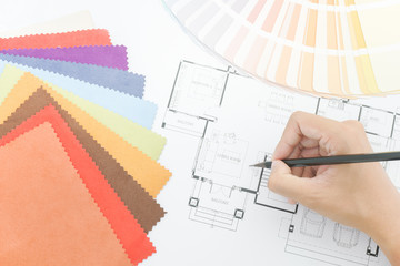 Close up hand writing on architectural drawing with color pallette and sample of fabric