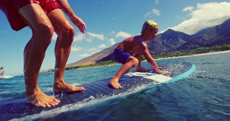 Father and son having fun surfing together at sunrise