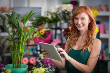 Crédence de cuisine en verre imprimé Fleuriste Smiling female florist using digital tablet in florist shop