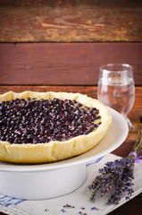 Bilberry, blueberry tart with lavender on white plate, wooden background