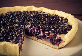 Bilberry, blueberry tart with lavender on white plate, wooden background