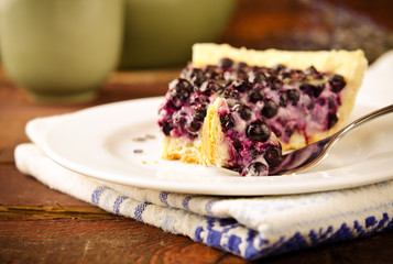Bilberry, blueberry tart with lavender on white plate, wooden background