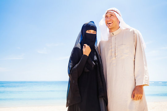 muslim couple on a beach wearing traditional dress