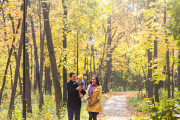 Obraz premium love, parenthood, family, season and people concept - smiling couple with baby in autumn park