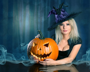 Witch with Halloween pumpkin. Beautiful blonde girl