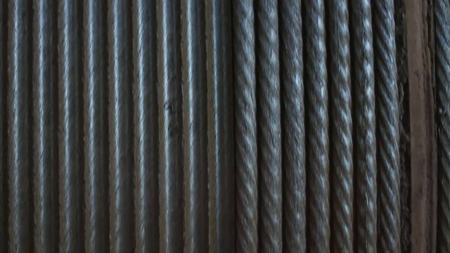 Steel wire rope is wound on the bay. Cable collecting winch drum rotating.