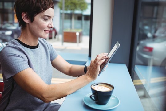 Businesswoman using digital tablet while having coffee