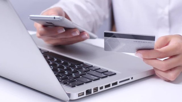 Girl doing shopping online via mobile and credit card. Close up