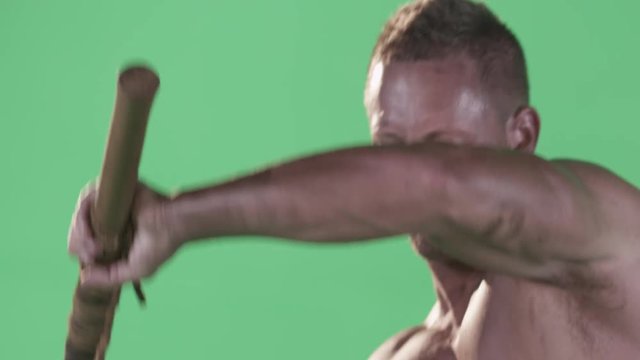 On a Green Screen a buff man with no shirt on, slams down a hammer 