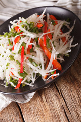 daikon salad with peppers and herbs closeup. vertical