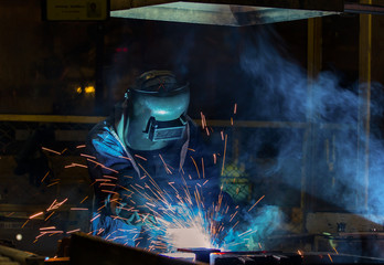 Worker with protective mask welding automotive part 