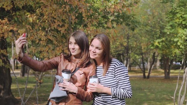 two young women take a selfie in autumn Park