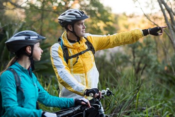 Fototapeta premium Biker couple with mountain bike pointing