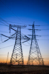 The silhouette of the evening electricity transmission pylon