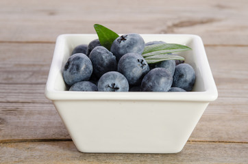  blueberries in a porcelain dish on wooden background