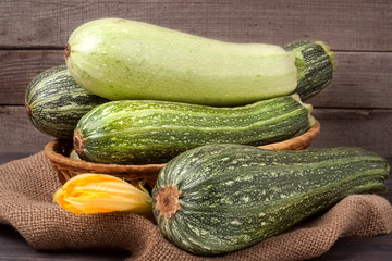 green zucchini and courgettes with a flower on sackcloth wooden background