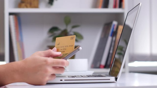 Online shopping. Female hand holding gold credit card and shopping online. Close up