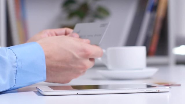 Man shopping online using digital tablet and gold credit card. Close up