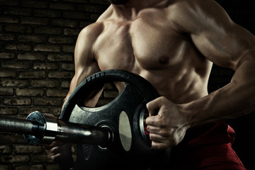 Sports background. Closeup photo of handsome bodybuilder guy prepare to do exercises with barbell...