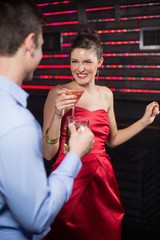 Smiling couple holding glass of beer and cocktail while dancing