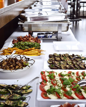 Party buffet with italian Antipasti and metal containers with cooked food.