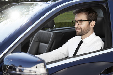 Businessman driving car, smiling