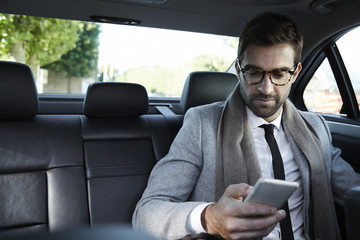Fototapeta na wymiar Businessman texting on smartphone in car