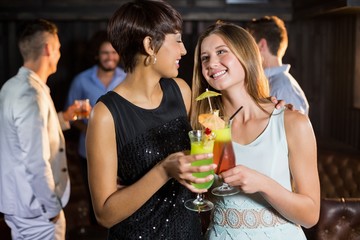 Female friends holding glass of cocktail in bar