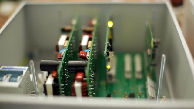 Electronic device in protective case, green circuit boards with blinking led in box.