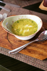 Noodle soup with green herbs in bowls on a wooden board.