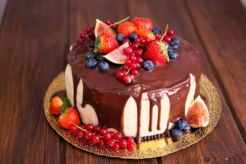 Birthday cake with cream and chocolate, fresh fruit and berries slide.