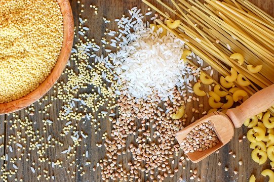 Gluten free cereals corn, rice, buckwheat, quinoa, millet and pasta and flour on brown wooden background