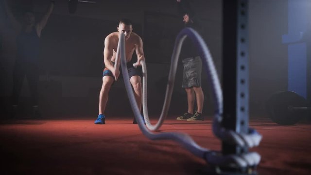 Young athlete doing crossfit exersise with ropes