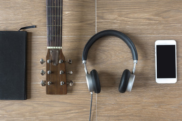 Flat Lay of Musician Stuffs on Table. Notebook, Guitar and Headphone on Wood Background.