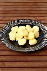 Gluten free gnocchi from corn flour on dark plate on brown wooden background
