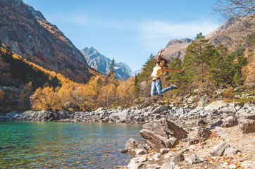 Fototapeta na wymiar Happy Woman jumping near lake and mountains