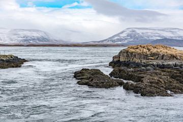 island with small red tower at port of stykkisholmur, fjord breidafjoerdur at peninsula snaefellsnes in winter with falling snow, west iceland