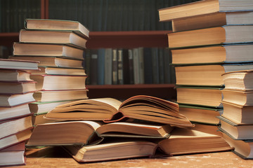 A stack  of many old books on the table-background of bookshelve