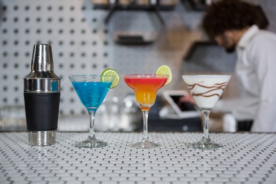 Various cocktails drinks and cocktail shaker on a bar counter