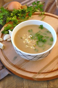 Healthy vegan soup from mung bean, coriander, garlic and onion in bowl on wooden background