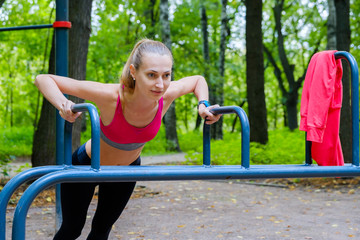 Fototapeta na wymiar Young slim woman doing workout in a training ground in a park