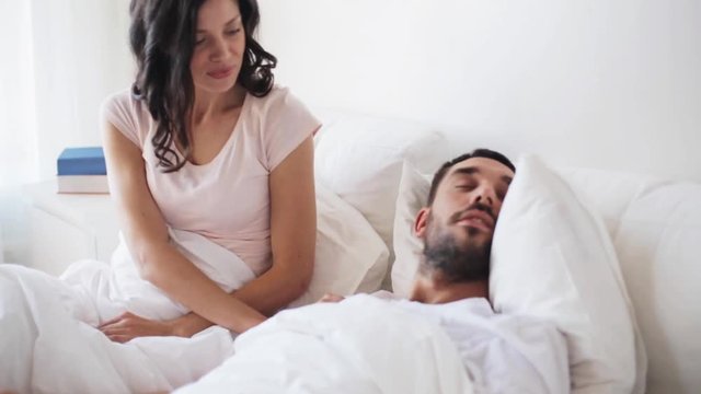 angry woman waking man sleeping in bed