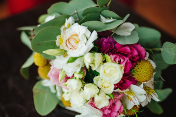 Pretty good wedding bouquet of various flowers with rings . Close-up