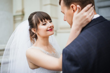 Naklejka premium Bride and groom at wedding Day walking Outdoors near architecture. Bridal couple, Newlywed woman and man embracing with love