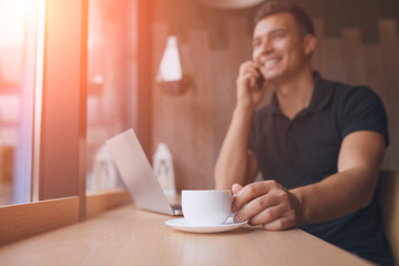 man working on net-book in a cafe, flare sun