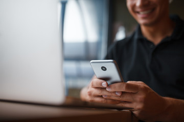 Young smart man working with laptop computer and smartphone