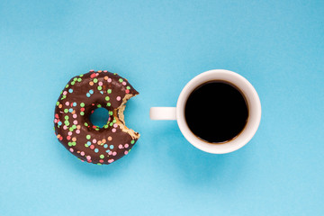Chocolate donuts with cup of coffee on the blue background.