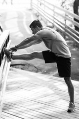 Young athlete in park doing exercises, black-and-white photo