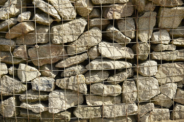 A whole page of a wall of dry caged stone background texture