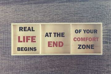 Real life begins at the end of your comfort zone. Inspirational quote written on wooden box